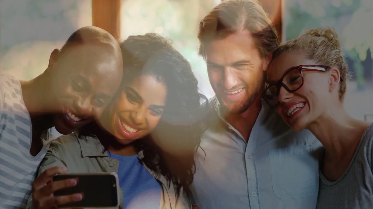 L'uomo a sinistra inclina il telefono, il gruppo si sporge mentre il bokeh si diffonde su volti e telefono, condivisione sui social media