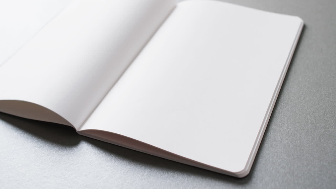 Close up of open blank book with copy space on gray background in slow motion