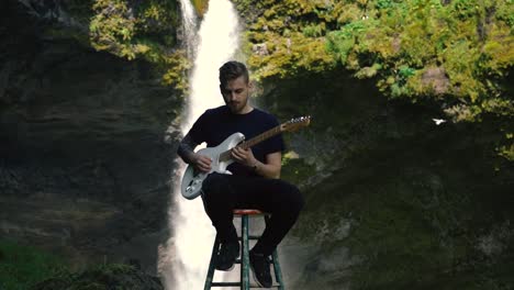 man playing guitar in front of a beautiful waterfall in iceland-15