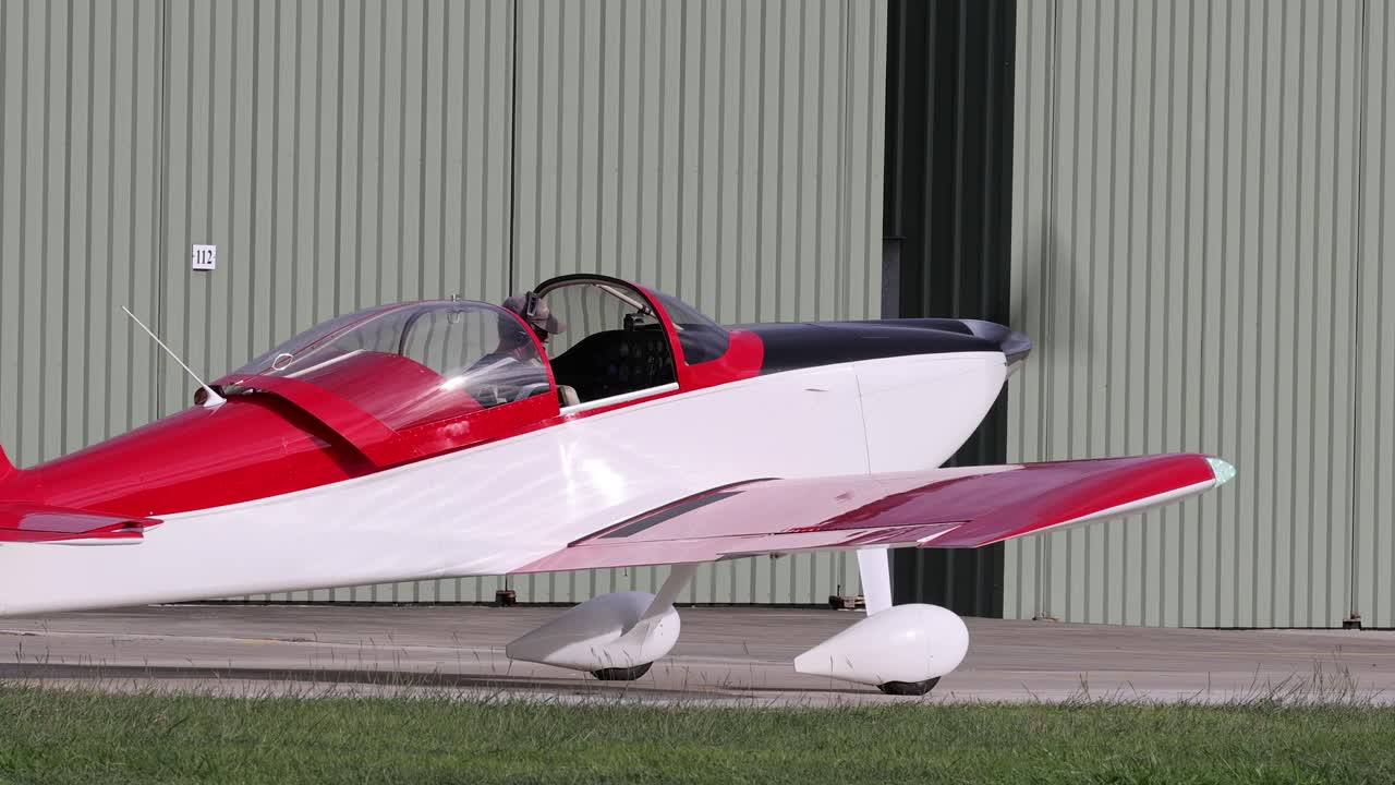 красный и белый самолет движется по взлетно-посадочной полосе аэропорта