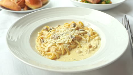 parmesan cheese is sprinkled over spaghetti pasta with mushrooms and cream sauce on a plate in italian restaurant