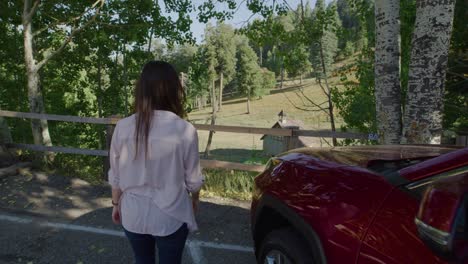 female actor walking to wood rail overlooking small little church