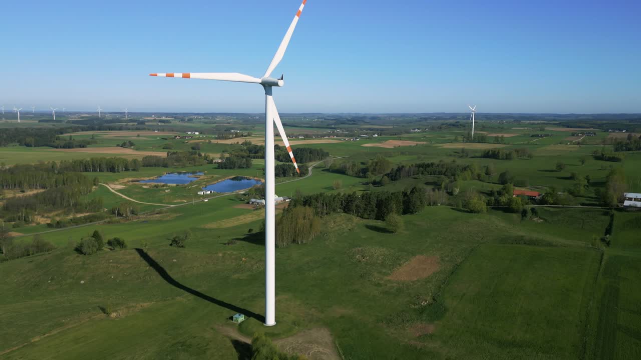 A slowly rotating propeller on a wind turbine in the middle of a green landscape