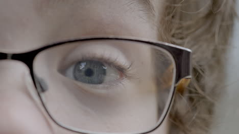 closeup of a young boy wearing glasses and his pretty blue eye as he makes a surprised expression