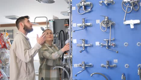 positive cute couple choosing tap in the bath in bathroom furniture shop positive cute couple choosing tap in the bath in bathroom furniture shop a young couple chooses a new faucet in a plumbing store