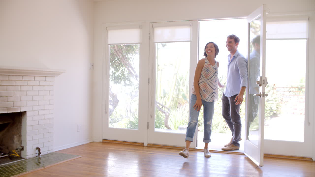 una pareja emocionada explora un nuevo hogar el día de la mudanza.