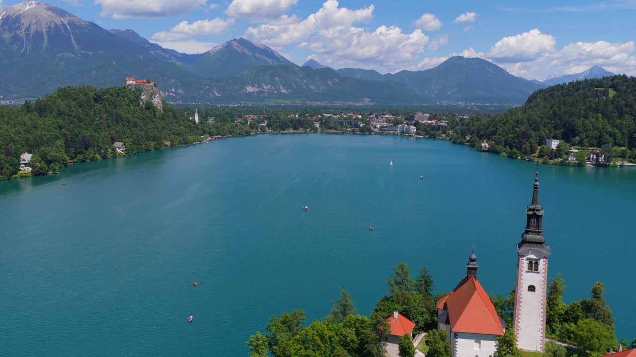 Chiesa sull'isola del Lago di Bled nel suo contesto completo con la costa circostante e le montagne distanti