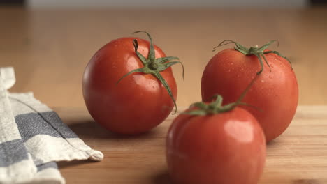 studio product shot of fresh tomatoes with water drops on it and cloth next to the tomatoes and blurred background in slow motion