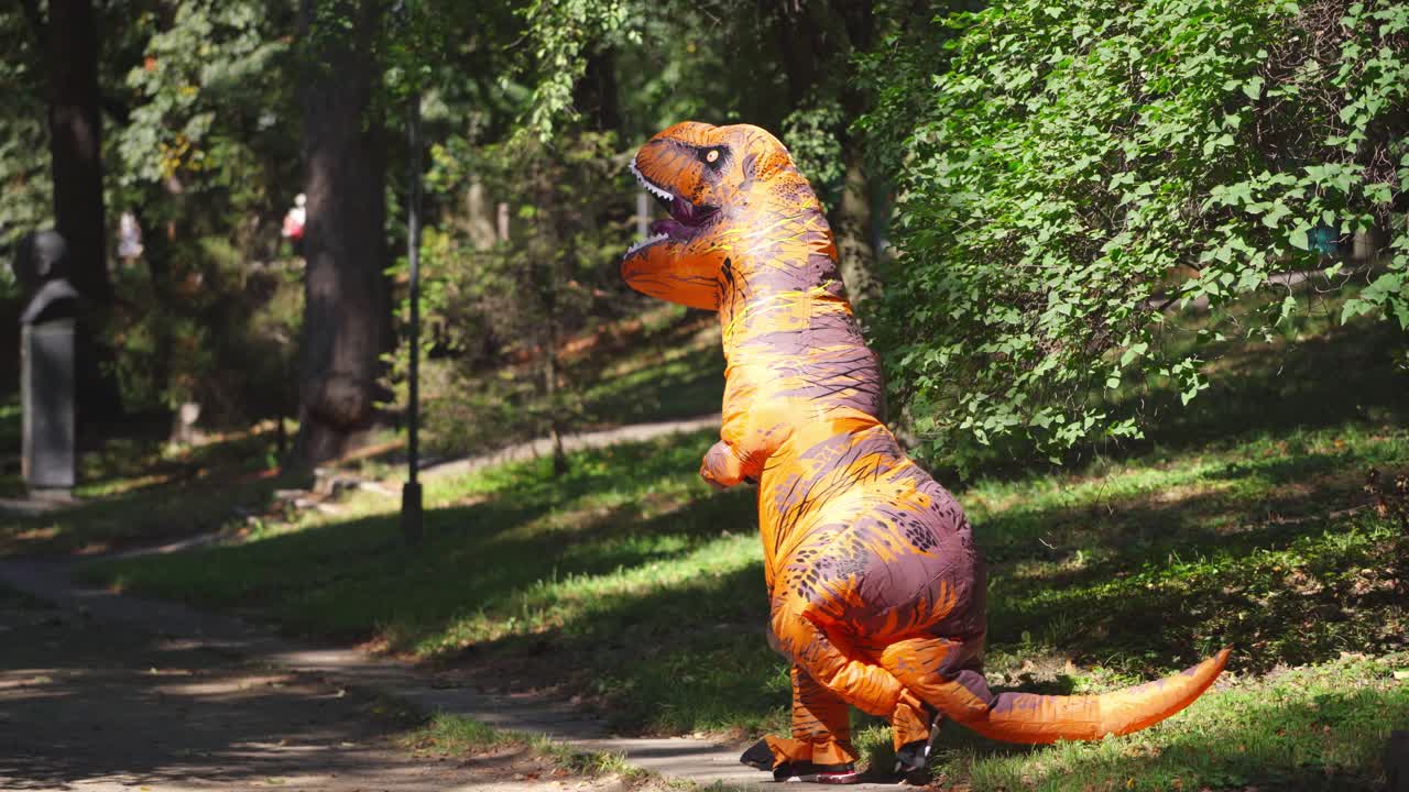 Joyful person in dragon costume. Funny person in dragon carnival suit having fun in the park in summertime.