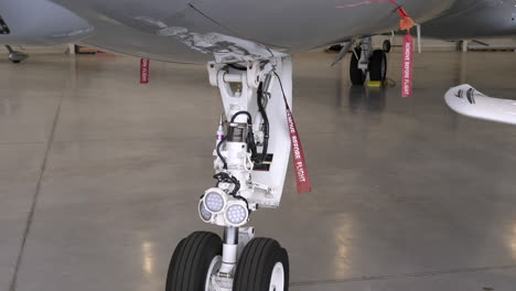 Tren-De-Aterrizaje-De-Un-Gran-Avión-De-Pasajeros-Con-Marcadores-De-Bandera-En-El-Hangar