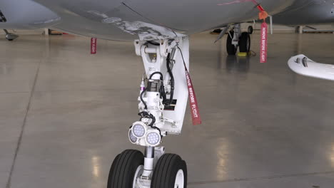 tren de aterrizaje de un gran avión de pasajeros con marcadores de bandera en el hangar