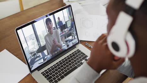 african american male college student holding notes while having a video call on laptop at home