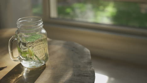 setting a glass mug with hot water and herbal tea on table