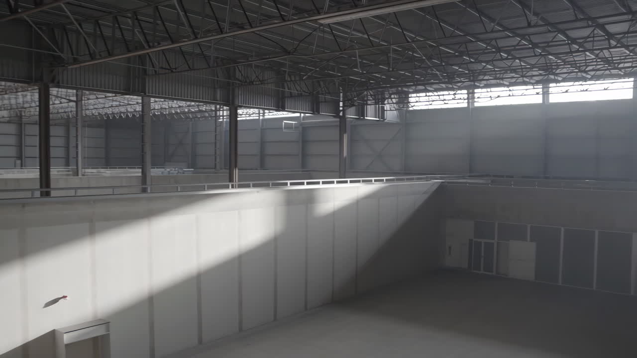 Empty Industrial Warehouse Interior with Sunlight and High Ceilings