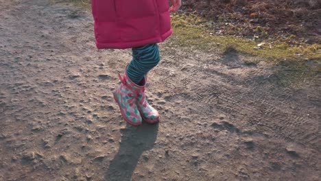 jovencita despreocupada caminando con botas de agua divirtiéndose en un parque con sombra