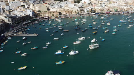 aerial view of harbour of marsaxlokk village with colorful boats in malta - drone shot