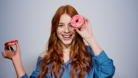 playful female person holding doughnuts indoors. woman sending kisses in studio