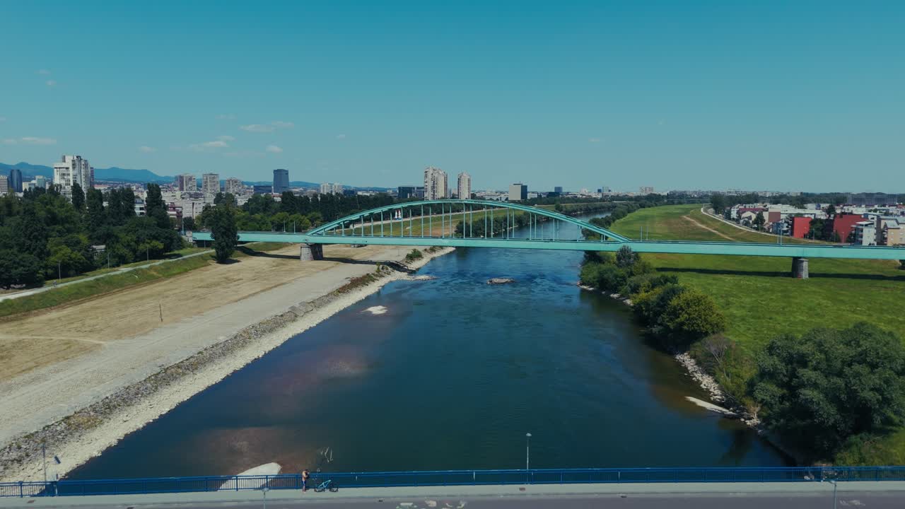 twin bridges crossing the Sava River in Zagreb with cityscape and greenery under a clear blue sky