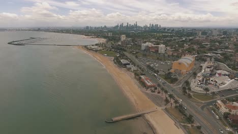 drone aerial over st kilda in melbourne showing the beach and pier on a cloudy day