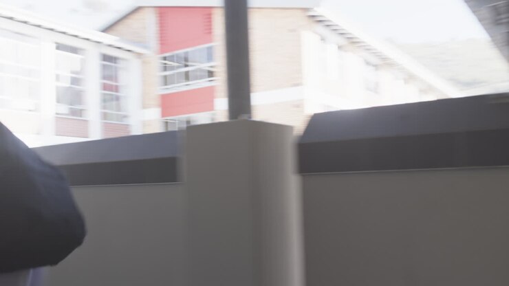 Nel corridoio della scuola, uno studente cammina con uno zaino e si affretta verso la lezione.