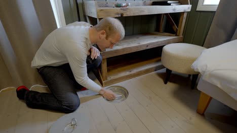 man opens floor hatch and places hand line with rubber lures inside lofoten hotel room