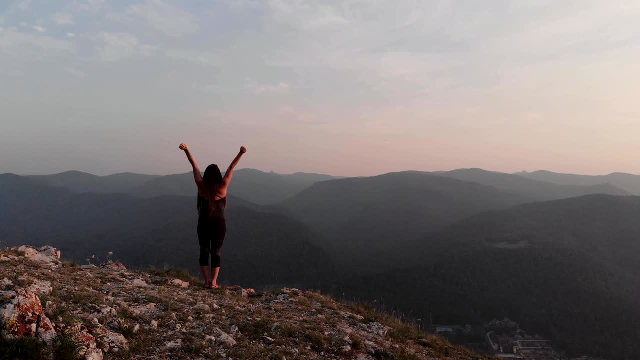una joven feliz de pie en el borde de un acantilado.