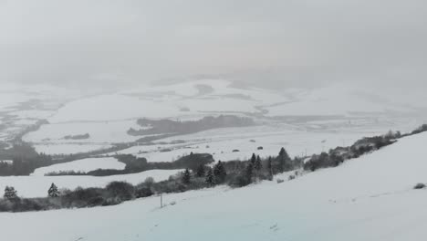 Avance-Aéreo-Hacia-El-Paisaje-Cubierto-De-Nieve-Con-Algo-De-Tráfico-En-El-Fondo