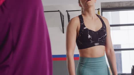 video of two diverse, exhausted, happy women high fiving after working out at a gym