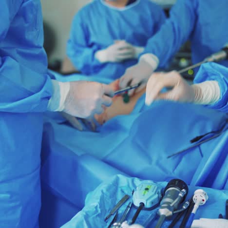surgery in the operating room. group of surgeons perform operation with surgery equipment. specialists in medical uniform doing surgery to a patient. close-up.