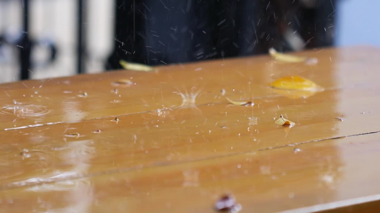 Raindrops falling down on wooden table