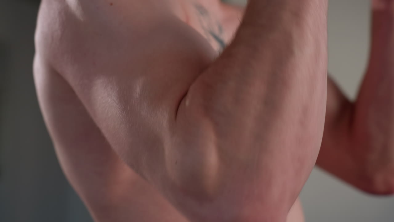 close up of muscular white man arm as he pulls resistance rope indoors, focus on strength and effort, showcasing skin texture, veins, and bicep movement during intense workout session