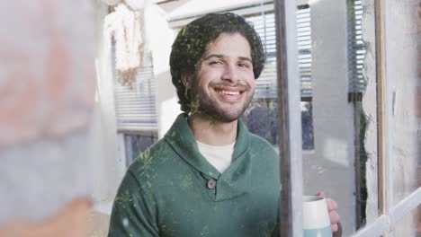 Portrait-of-happy-caucasian-man-drinking-coffee-and-looking-out-window-at-home,-slow-motion