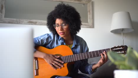 mujer negra positiva tocando la guitarra en casa