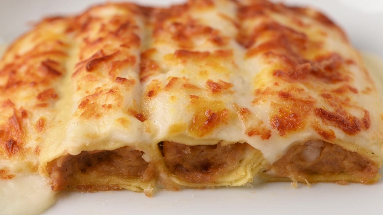 Cannelloni di carne al forno con formaggio e salsa besciamella.