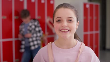 Video-portrait-of-happy-schoolgirl-standing-in-school-corridor