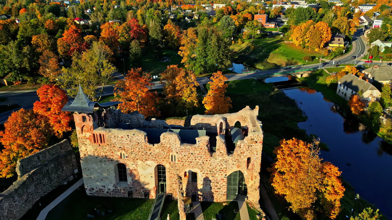 Aerial View Of Dobele Castle Ruins On Banks Of Berze River During Autumn In Zemgale, Latvia. orbiting drone shot