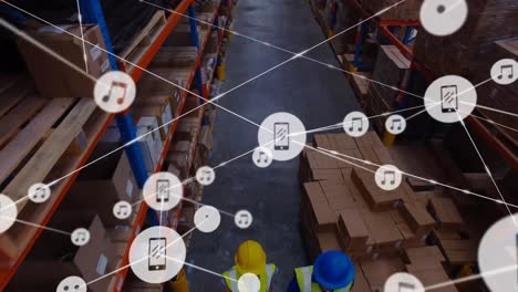 animation of network of digital icons over aerial view of workers working at warehouse