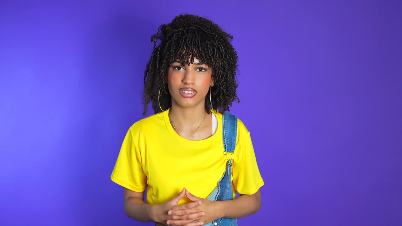 Mulher com camisa amarela e macacão jeans