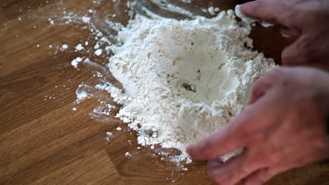 hands kneading dough on wooden surface for homemade bread