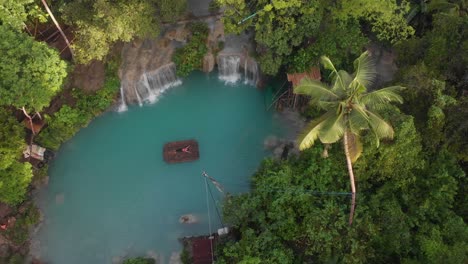 Drohnenaufnahme,-Seitliche-Aufnahme-Eines-Mädchens,-Das-Auf-Einem-Bambusfloß-An-Den-Cambugahay-Fällen-Auf-Der-Insel-Siquijor-Liegt,-Filmische-Drohnenantenne-In-4k