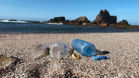 plastic pollution on a sandy beach with ocean waves and rocks