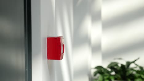 a red fire alarm button on a white wall