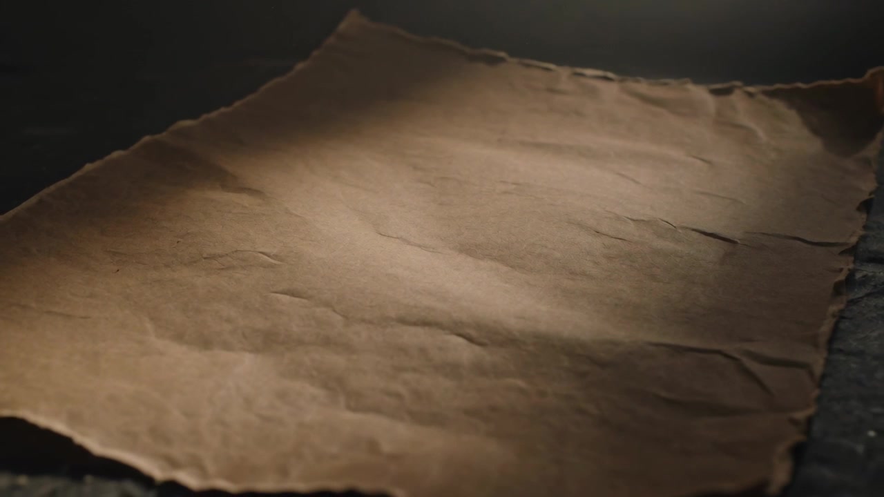 Shifting camera revealing crinkled parchment sheet on tabletop, showing creases under warm light