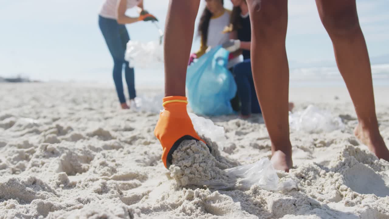 다양한 여성 친구 들 이 해변 에서 쓰레기 가방 에 쓰레기 를 넣고 있다