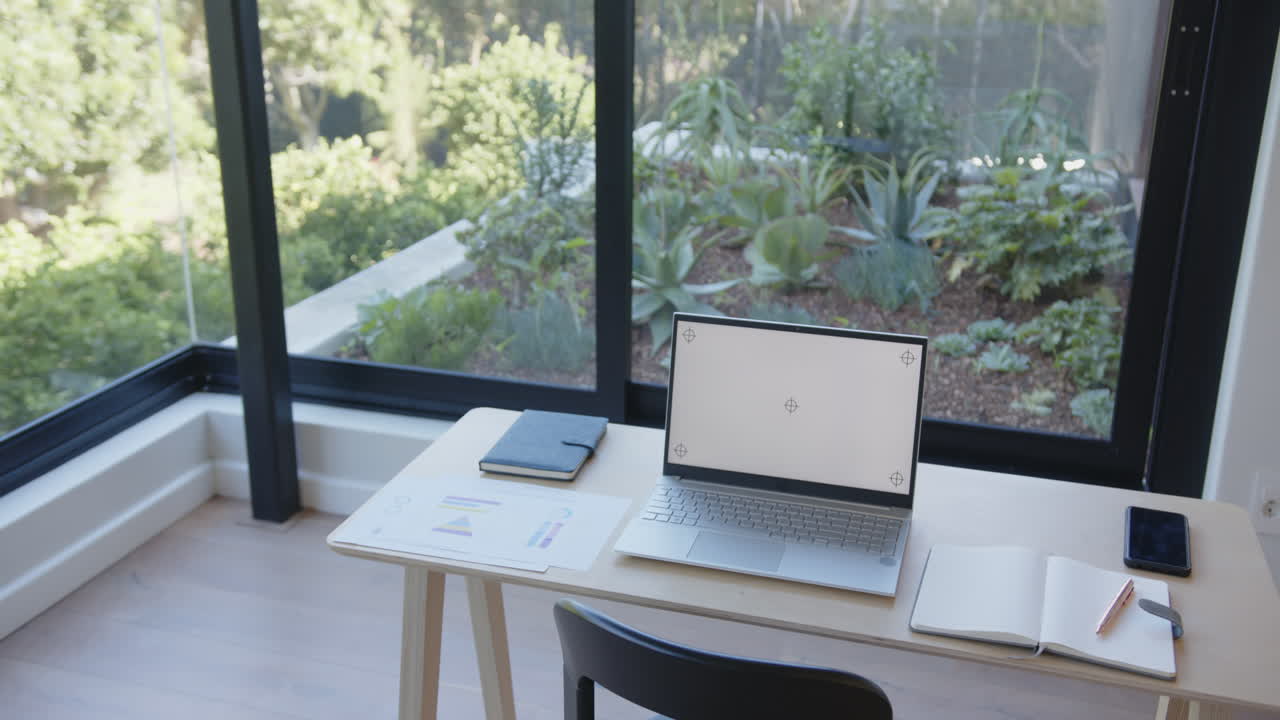 Laptop and tablet on desk in home office with garden view, ready for work, copy space