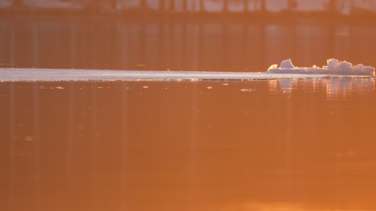 capa de hielo que se derrite lentamente arrastrada por la corriente del río al atardecer