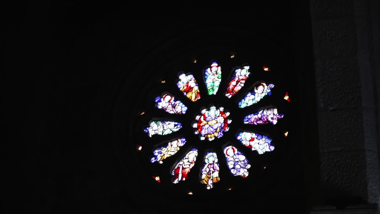 Vibrant stained glass rose window shines in a dark church interior, creating a serene glow