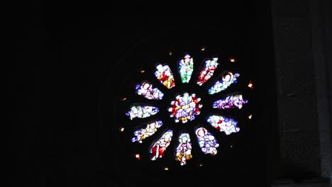 vibrant stained glass rose window shines in a dark church interior, creating a serene glow