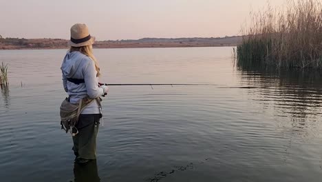 a beautiful girl catching a fish in a calm african lake