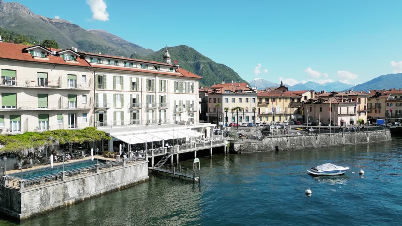 Waterfront view of Menaggio with historic buildings, moored boats, and alpine backdrop. Menaggio, Lago di Como, Italy